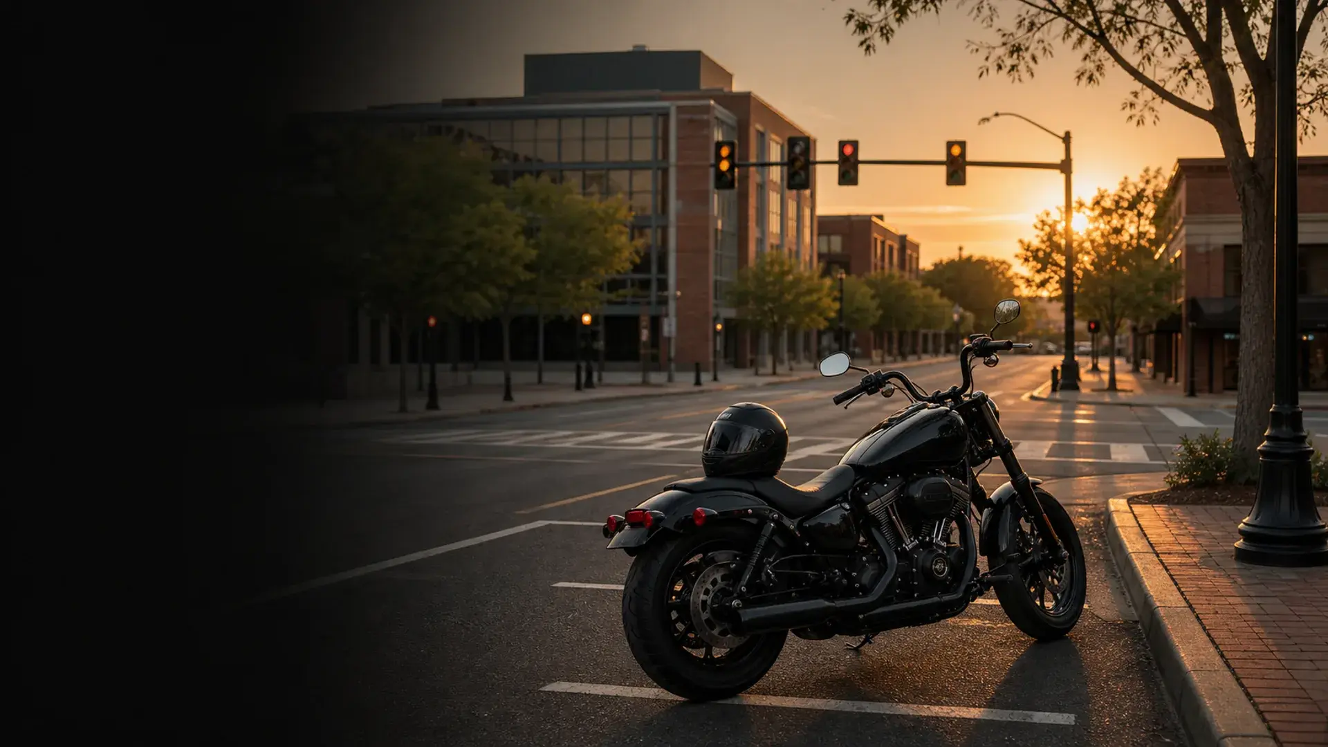 Motorcycle parked safely near a Norman campus-area intersection with traffic signals at golden hour