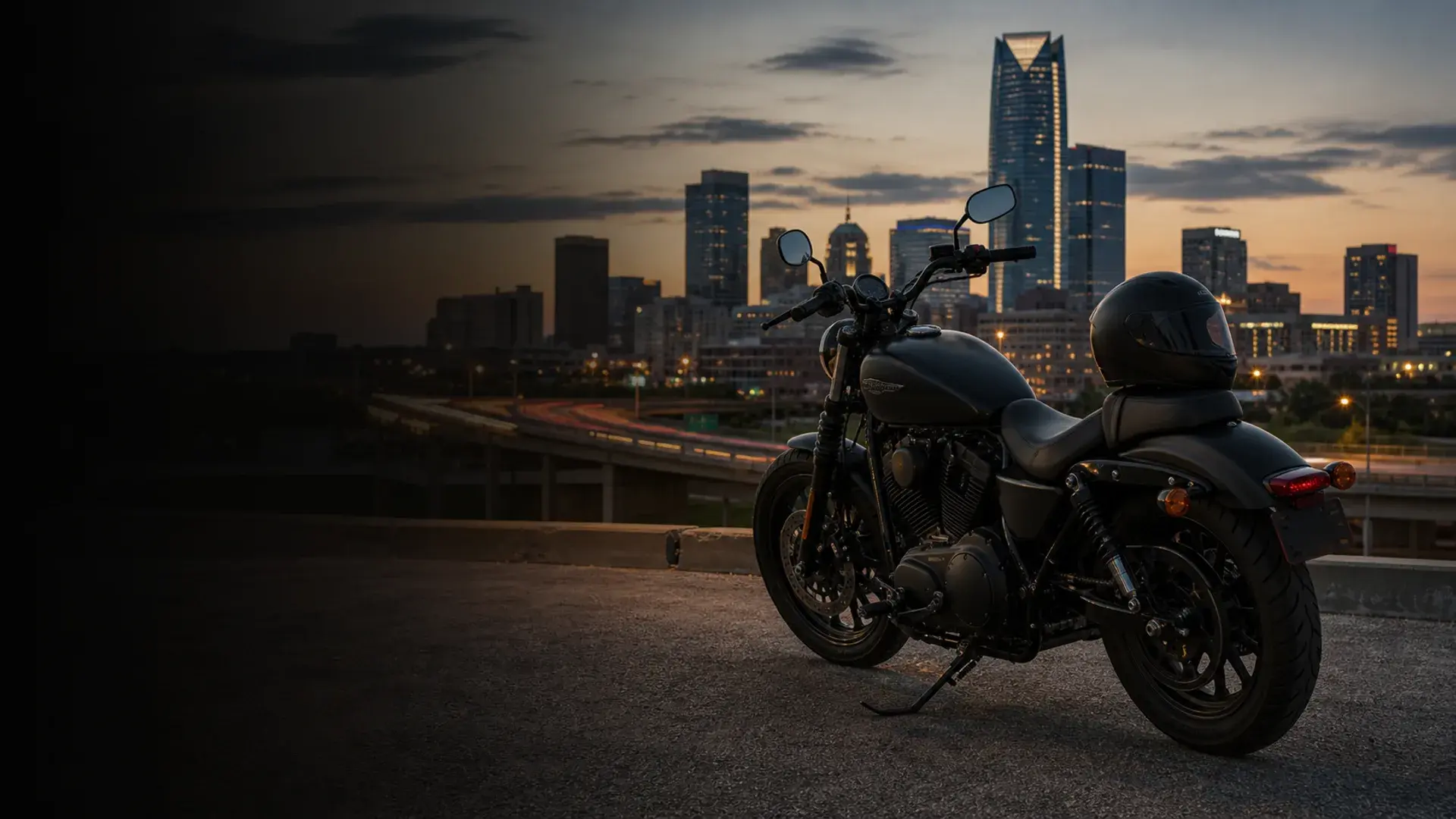 Motorcycle parked safely at an Oklahoma City overlook with downtown skyline and interstate lanes at dusk