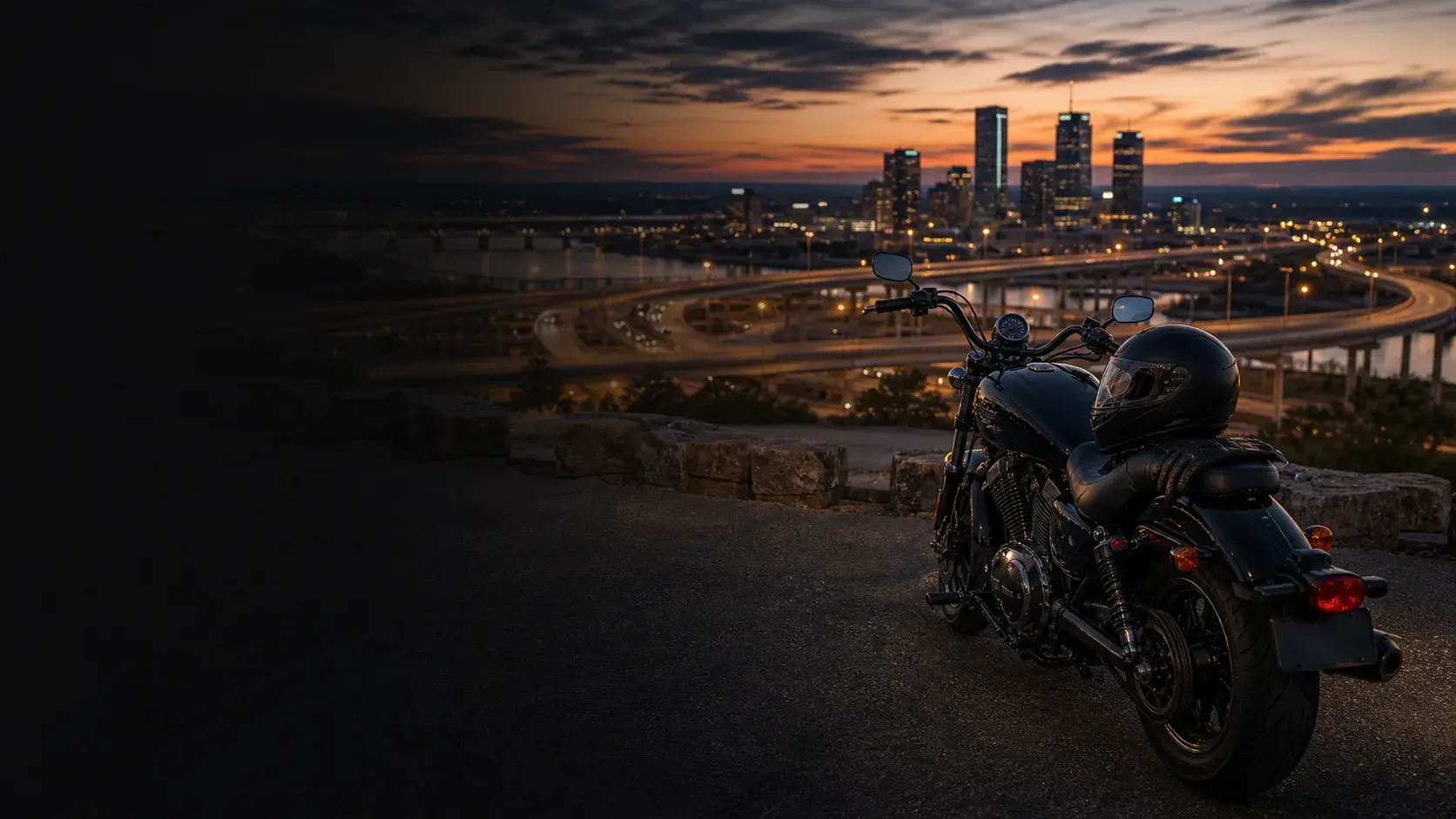 Motorcycle parked safely above Tulsa expressway ramps and skyline at dusk