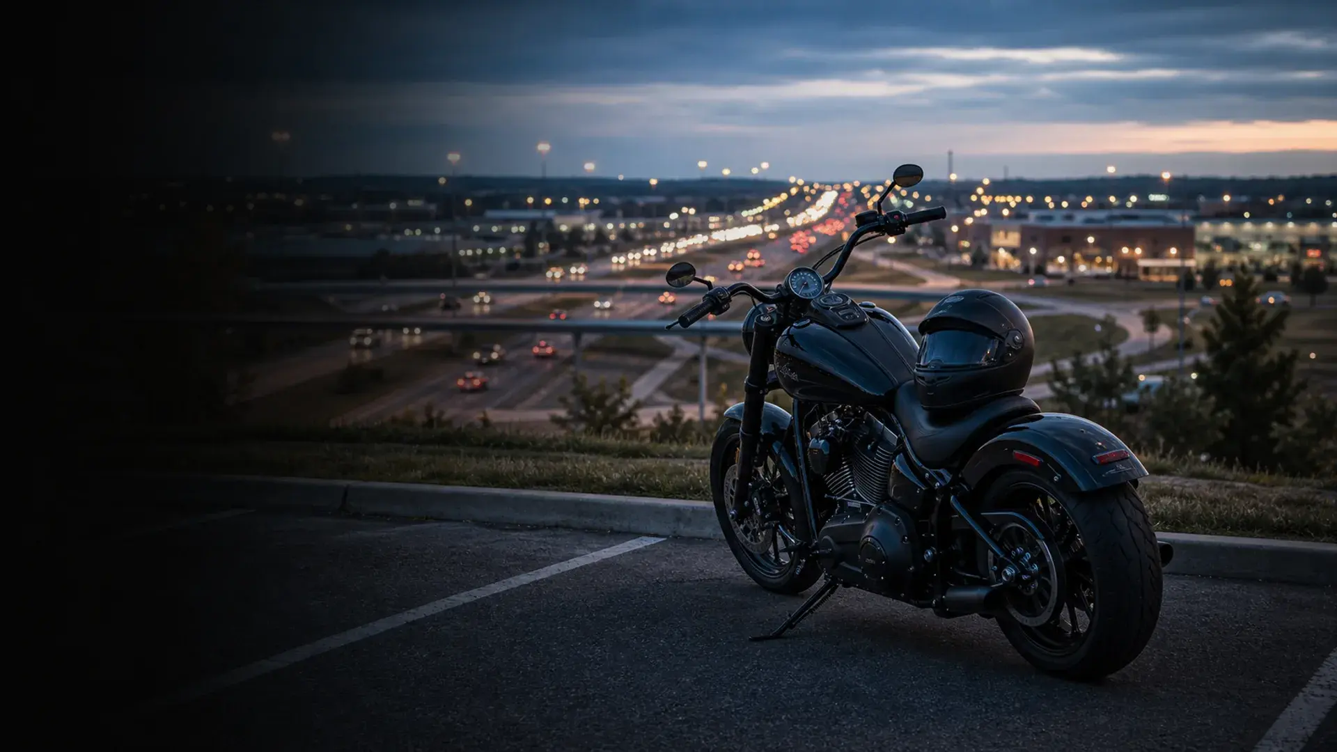 Motorcycle parked safely above a Broken Arrow commuter corridor with expressway lights at blue hour